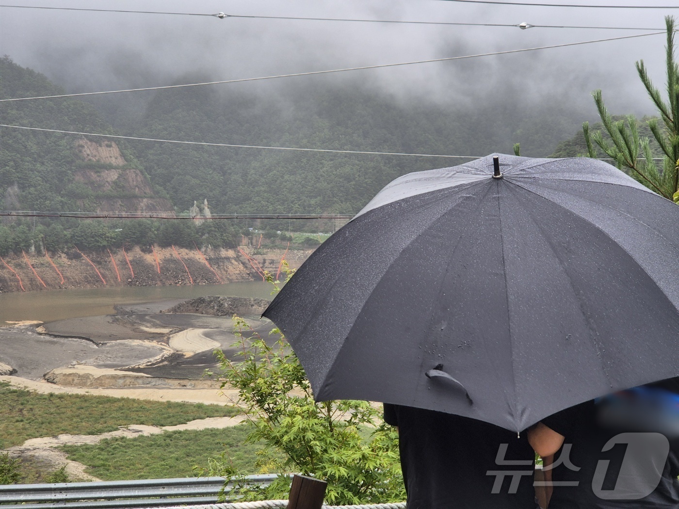 (강릉=뉴스1) 윤왕근 기자 = 극심한 가뭄을 겪고 있는 강원 강릉지역에 많은 비가 내린 13일 오전 우산을 쓴 시민이 마른 저수지에 내리는 단비를 바라보고 있다. 2025.9.1 …