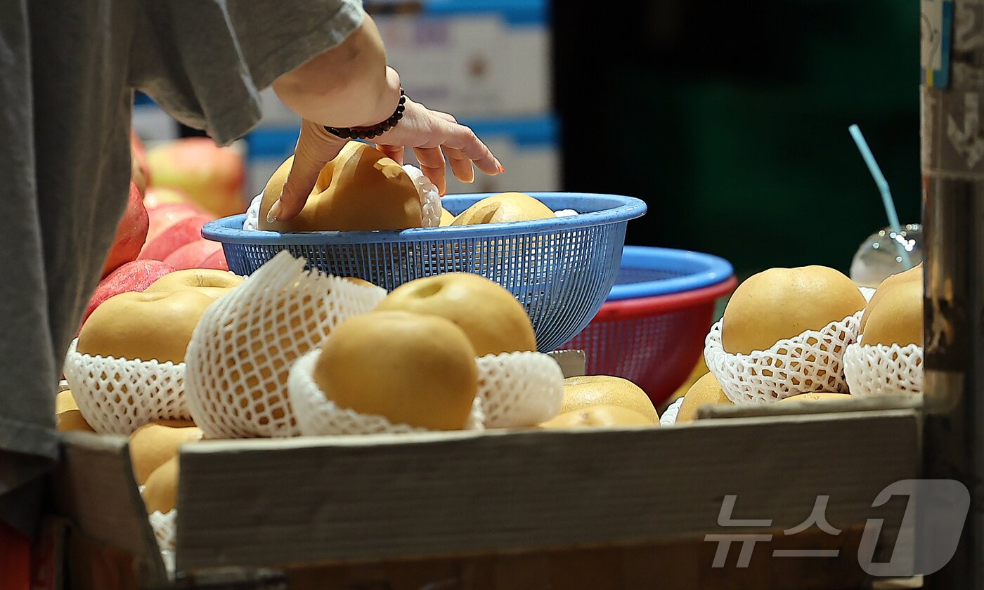 본문 이미지 - 14일 서울 동대문구 청량리 전통시장을 찾은 시민이 배를 구매하고 있다. 2025.9.14/뉴스1 ⓒ News1 김진환 기자
