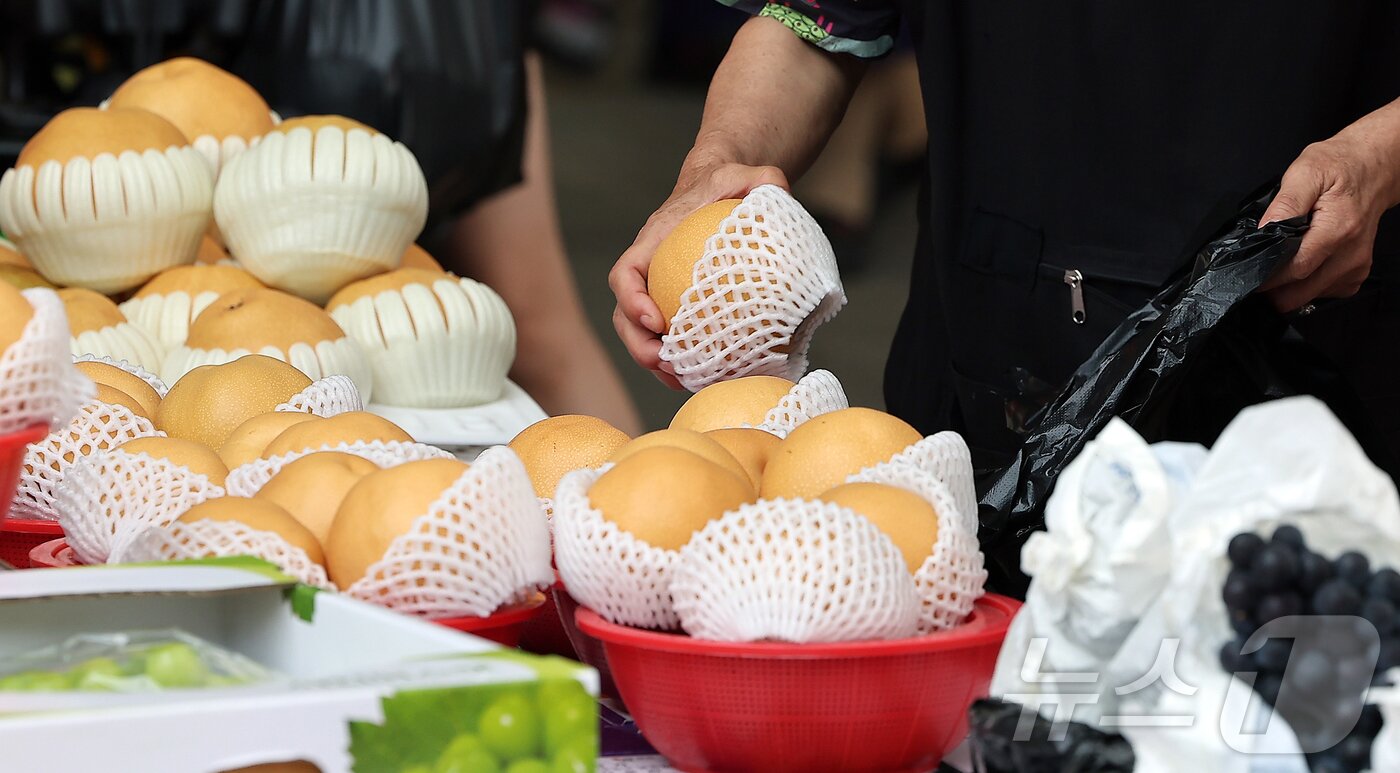 본문 이미지 - 14일 서울 동대문구 청량리 전통시장을 찾은 시민이 배를 구매하고 있다. 2025.9.14/뉴스1 ⓒ News1 김진환 기자