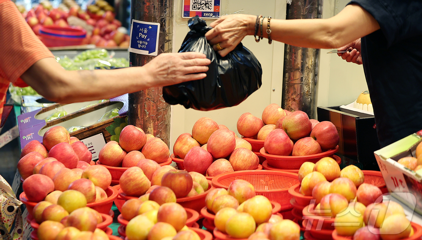 (서울=뉴스1) 김진환 기자 = 14일 서울 동대문구 청량리 전통시장을 찾은 시민이 사과를 구매하고 있다.이날 한국물가정보에 따르면, 지난 12일 기준 전국 전통시장에서 4인 가족 …