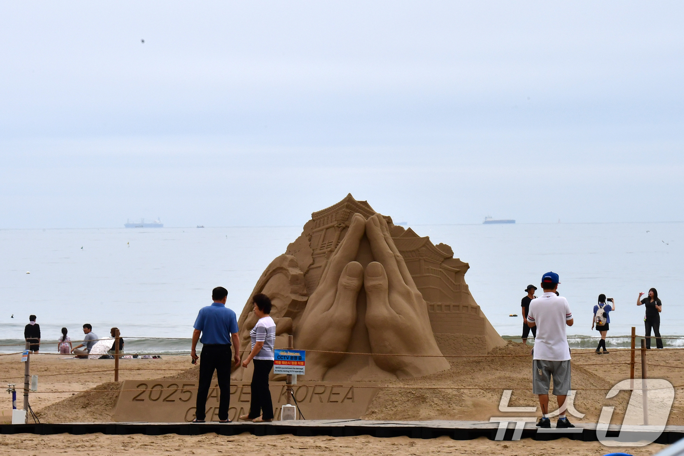 (포항=뉴스1) 최창호 기자 = 14일 경북 포항시 북구 영일대해수욕장 백사장에서 시민들이 APEC 2025 정상회의 성공 개최를 염원하는 모래조각을 지켜보고 있다. 2025.9. …