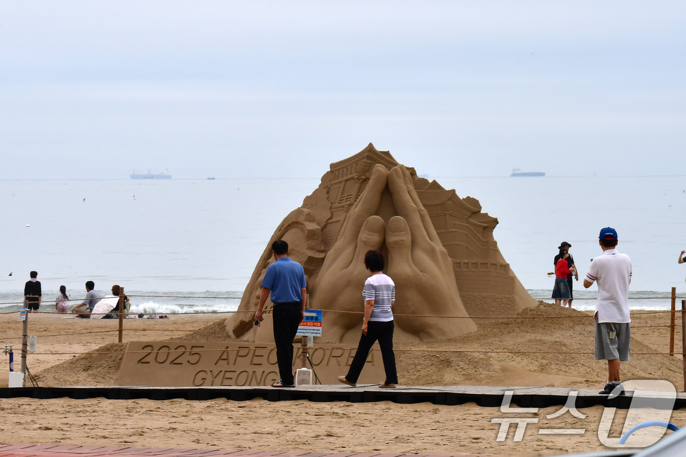 (포항=뉴스1) 최창호 기자 = 14일 경북 포항시 북구 영일대해수욕장 백사장에서 시민들이 APEC 2025 정상회의 성공 개최를 염원하는 모래조각을 지켜보고 있다.  2025.9 …