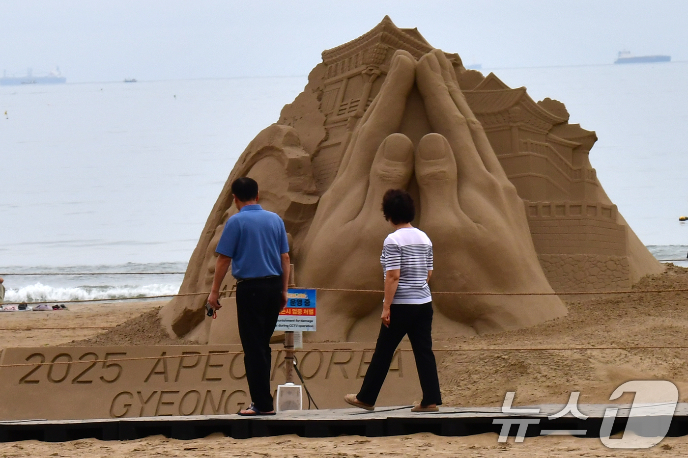 (포항=뉴스1) 최창호 기자 = 14일 경북 포항시 북구 영일대해수욕장 백사장에서 시민들이 APEC 2025 정상회의 성공 개최를 염원하는 모래조각을 지켜보고 있다. 2025.9. …