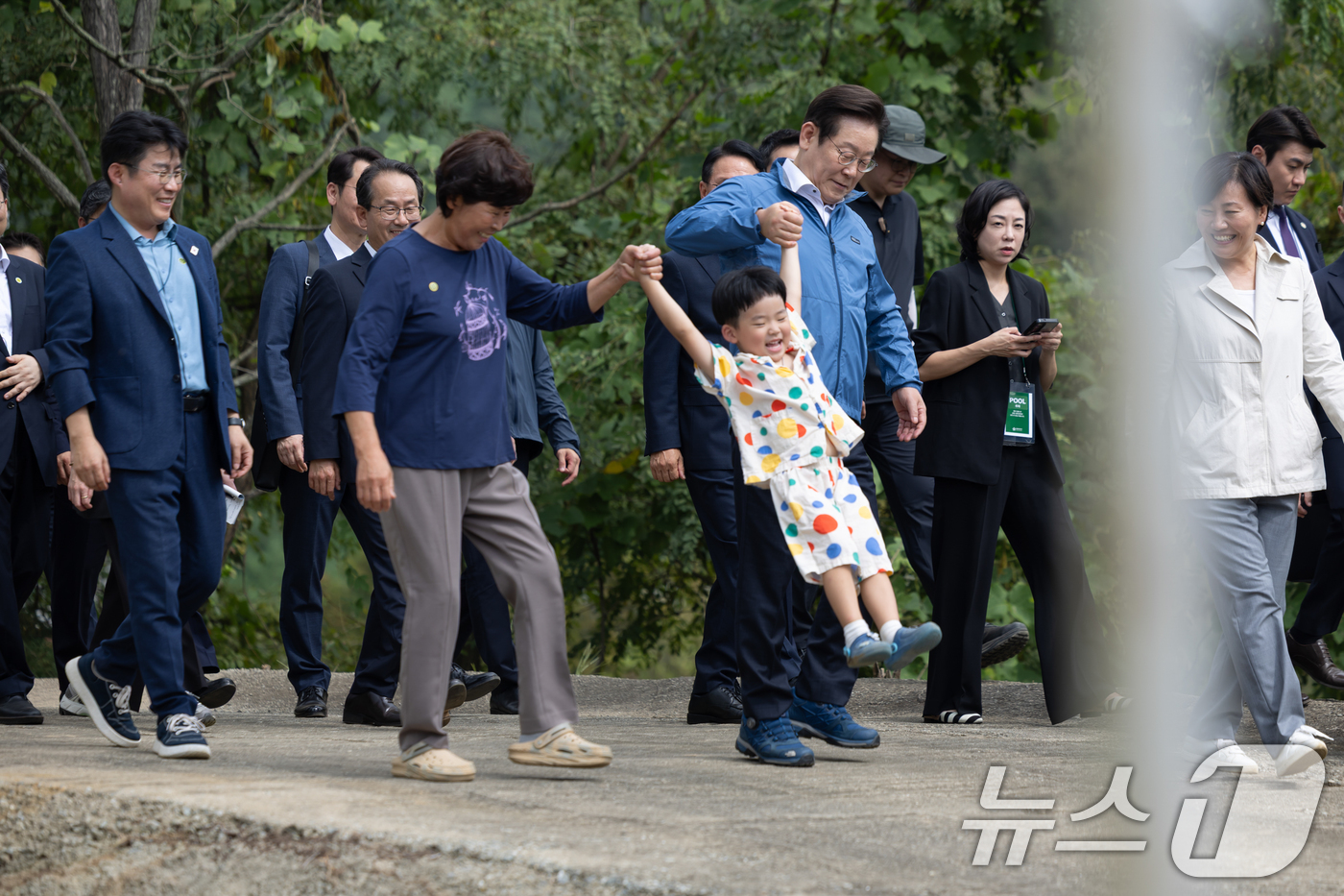 (서울=뉴스1) 허경 기자 = 이재명 대통령이 16일 세종시 전동면 조일농원에서 박성호 조일농원 대표 가족의 손을 잡고 청년 농업인 간담회장으로 이동하고 있다. (대통령실 제공. …