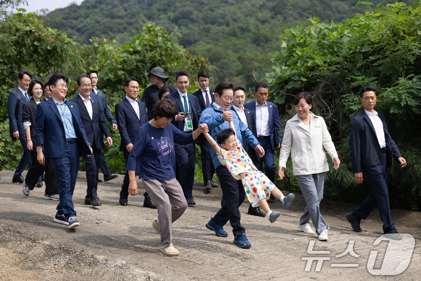 (서울=뉴스1) 허경 기자 = 이재명 대통령이 16일 세종시 전동면 조일농원에서 박성호 조일농원 대표 가족의 손을 잡고 청년 농업인 간담회장으로 이동하고 있다. (대통령실 제공. …