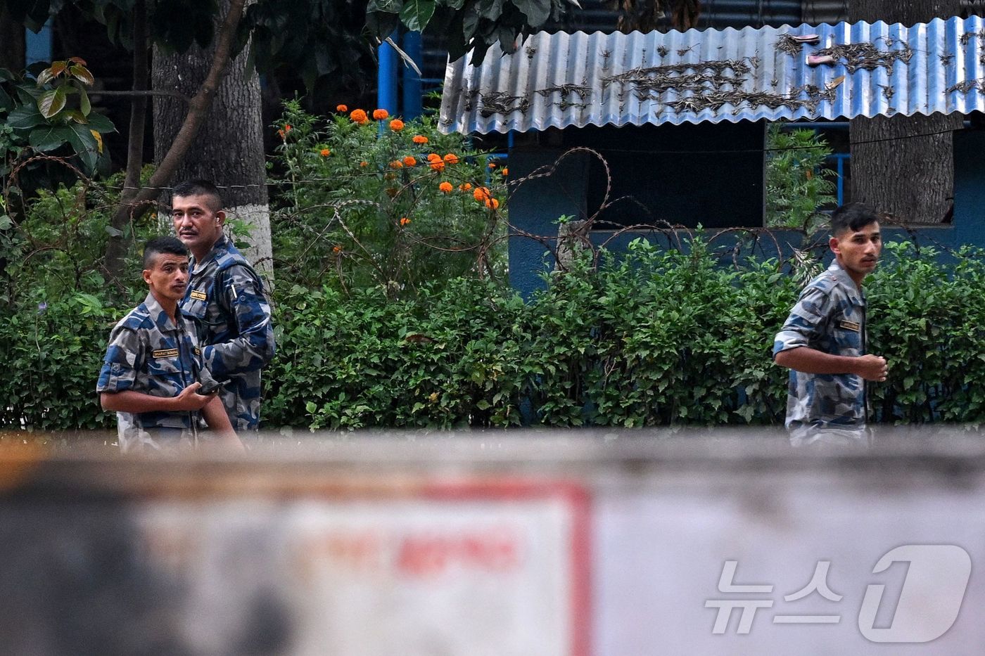 (AFP=뉴스1) 권영미 기자 = 15일 네팔 카트만두의 불탄 나쿠 교도소 정문 앞을 경비 요원이 지나가고 있다. 지난주 네팔 전역에서 벌어진 시위로 인해 네팔 정부가 붕괴되었으며 …