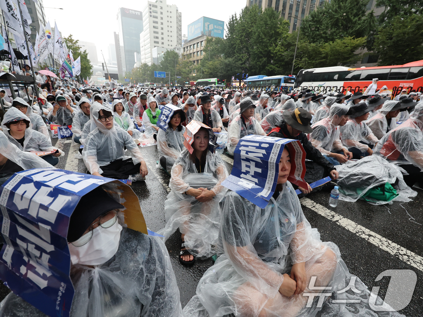 (서울=뉴스1) 황기선 기자 = 민주노총 공공운수노조 조합원들이 17일 오후 서울 세종대로 숭례문앞에서 손팻말로 비를 가리며 '공공기관 노동자 총파업 총력투쟁대회'를 진행하고 있다 …