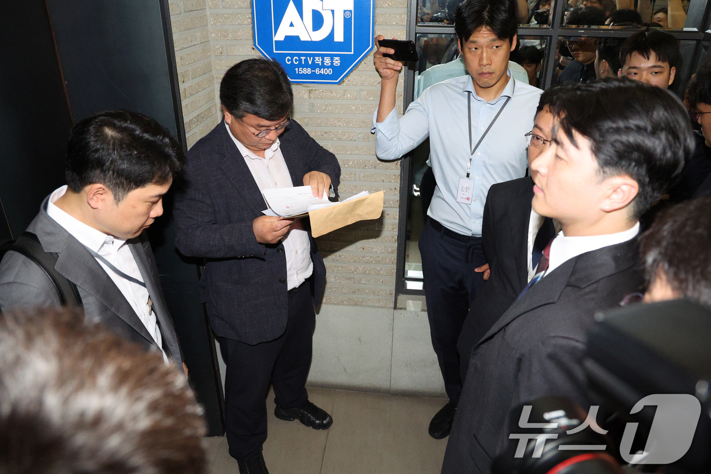 (서울=뉴스1) 신웅수 기자 = 국민의힘 당원명부 압수수색에 나선 김건희특검 수사관들이 18일 서울 여의도 중앙당사에서 국민의힘 변호사에게 압수수색 영장을 제시하고 있다. 2025 …