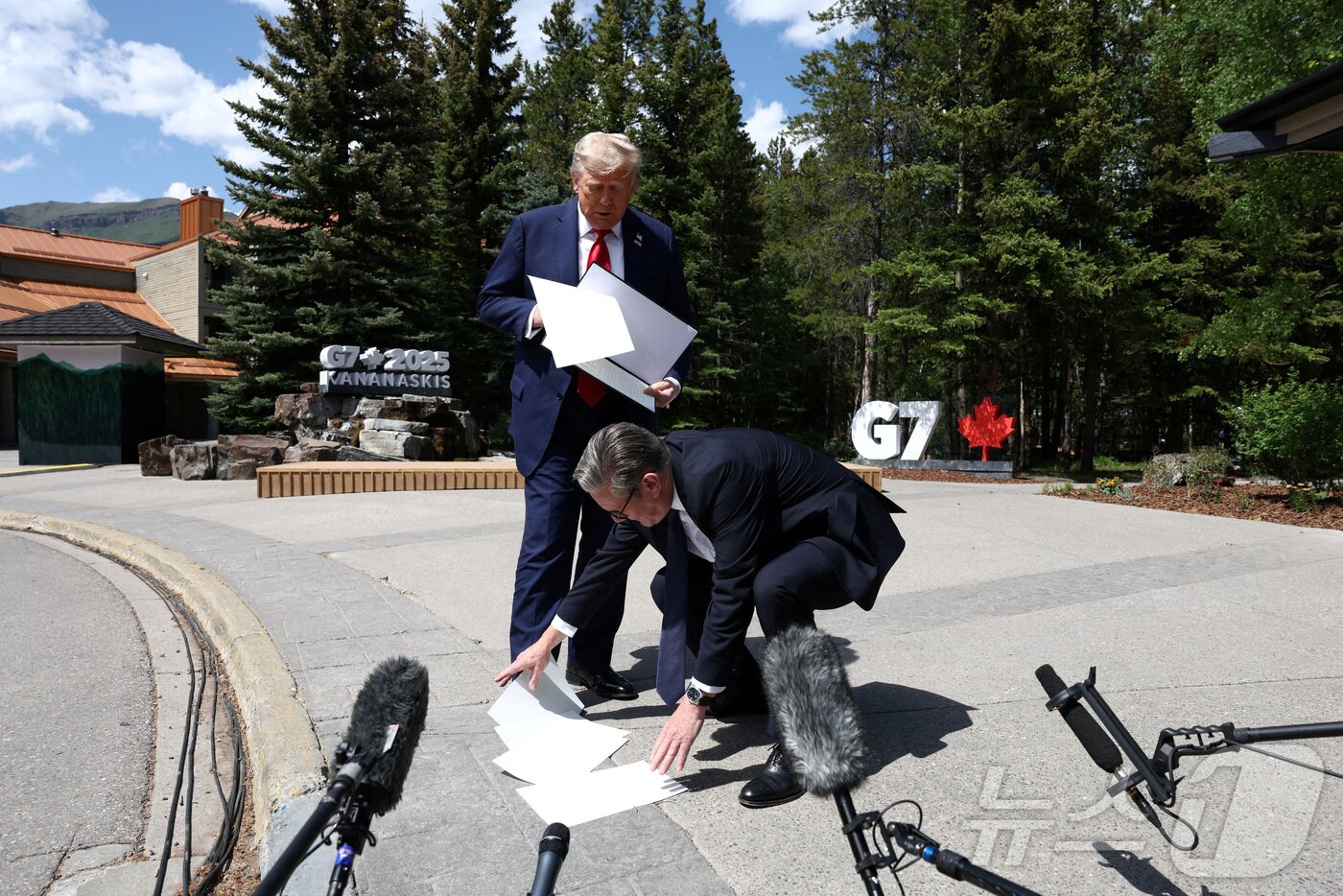 본문 이미지 - 키어 스타머 영국 총리가 2025년 6월 16일 캐나다 앨버타주 캐내내스키스에서 열린 주요 7개국&#40;G7&#41; 정상회의 도중, 도널드 트럼프 미국 대통령이 기자들과 이야기하는 동안 떨어뜨린 서류를 주워주고 있다. 2025.6.16 ⓒ 로이터=뉴스1 ⓒ News1 강민경 기자
