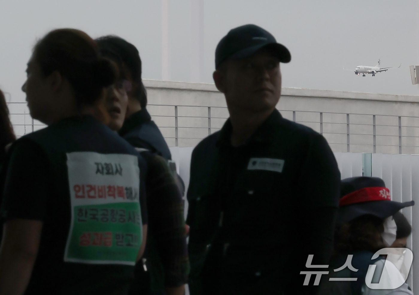 (인천공항=뉴스1) 박정호 기자 = 19일 오전 인천국제공항 2터미널에서 안전한 일터·안전한 공항을 위한 전국공항노동자 총파업 대회 참석 조합원들 뒤로 항공기가 착륙하고 있다.전국 …