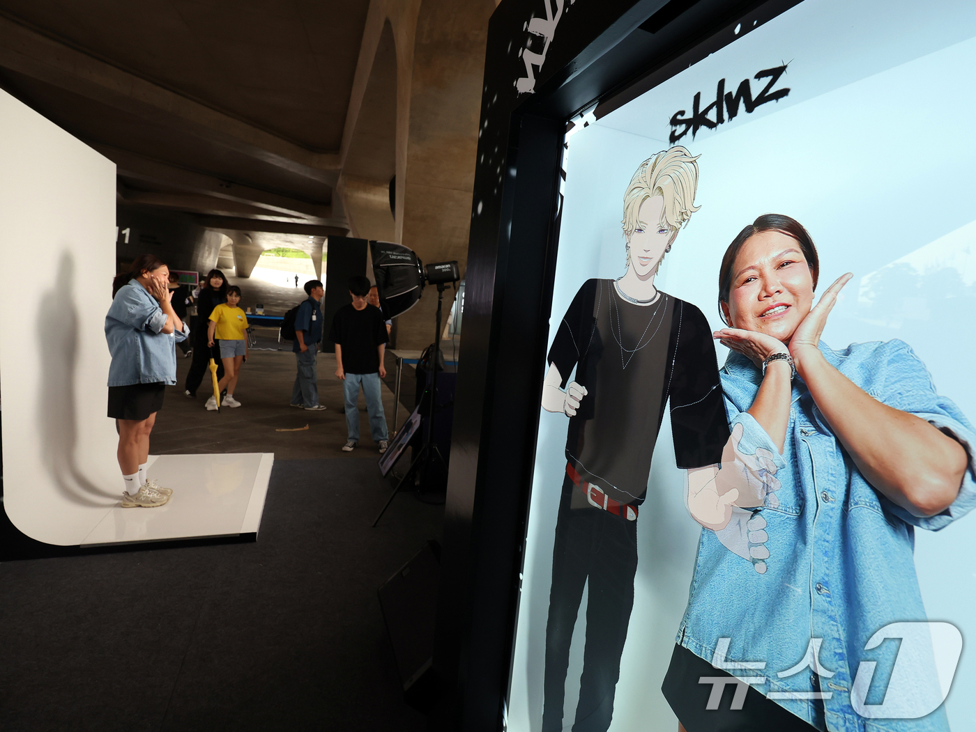 (서울=뉴스1) 황기선 기자 = 19일 서울 중구 동대문디자인플라자(DDP)에서 열린 '엔터테크 서울 2025'에서 외국인 관람객이 'K-버추얼 아이돌' 스킨즈와 홀로그램 라이브 …