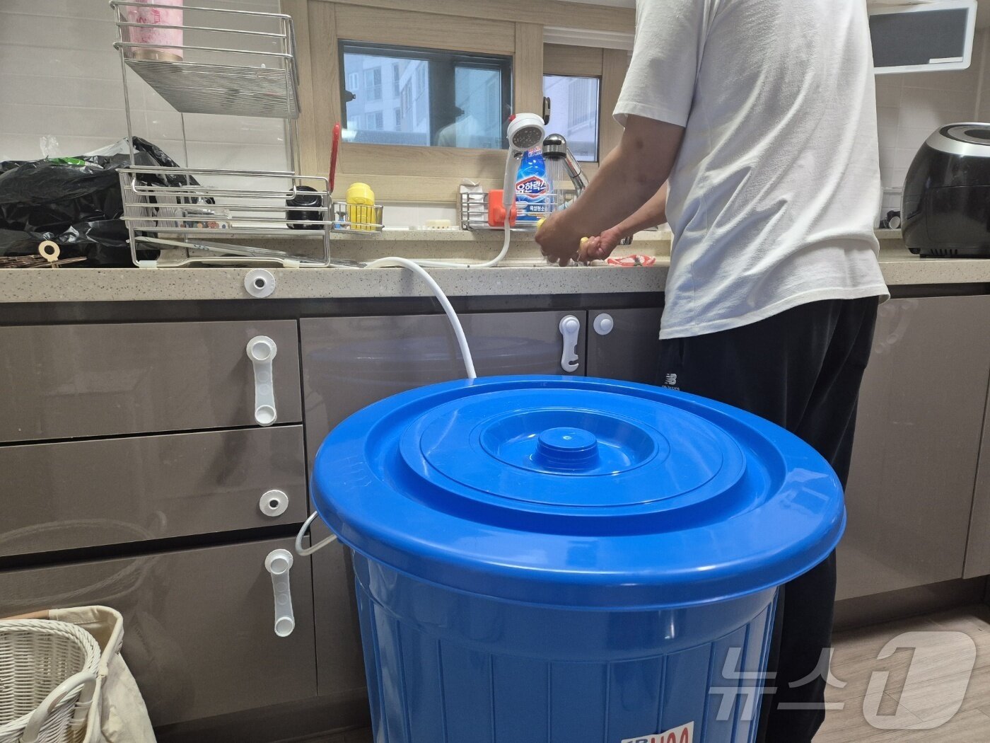 본문 이미지 - 강원 강릉지역 저수조 용량 100톤 이상 아파트 113곳에 대한 시간제 제한급수가 풀린 지난 19일 저녁 강릉 회산동의 한 아파트 주민이 수돗물을 이용해 설거지를 하고 있다. 싱크대 근처에 그동안 받아놓은 물을 아끼려고 달아놓은 샤워헤더와 물통이 놓여 있다.2025.9.19/뉴스1 ⓒ News1 윤왕근 기자