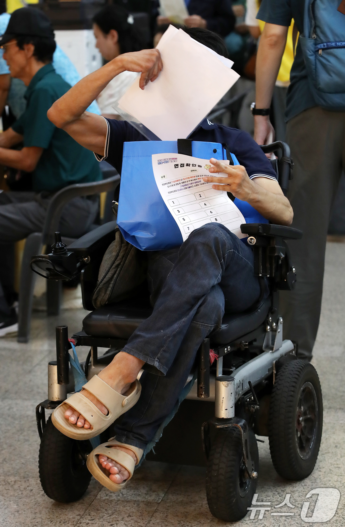 (부산=뉴스1) 윤일지 기자 = 2일 부산 연제구 부산시청 로비에서 열린 '2025 부산시 장애인 진로·취업 박람회'에서 한 구직자가 면접을 보기 위해 면접확인증 등 서류를 살펴보 …