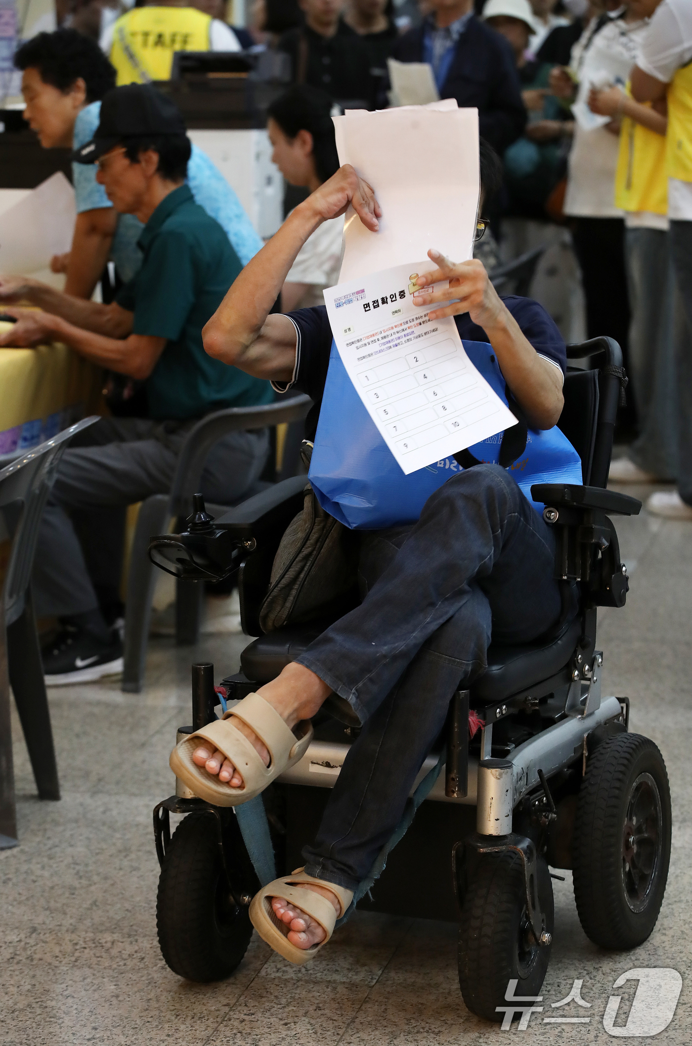 (부산=뉴스1) 윤일지 기자 = 2일 부산 연제구 부산시청 로비에서 열린 '2025 부산시 장애인 진로·취업 박람회'에서 한 구직자가 면접을 보기 위해 면접확인증 등 서류를 살펴보 …