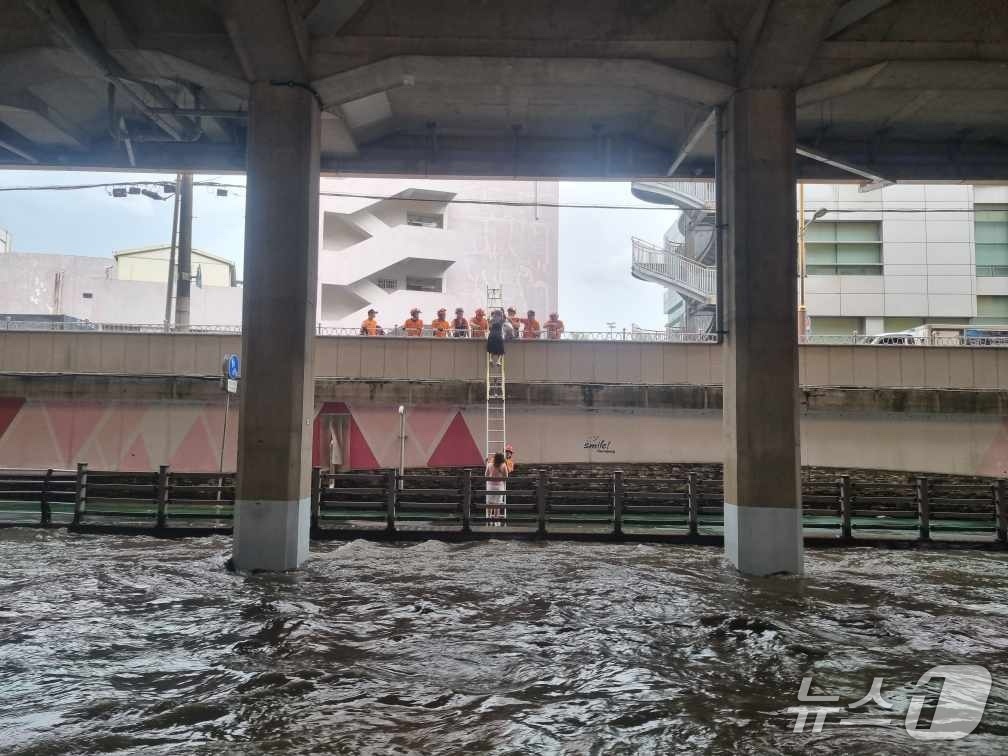(부산=뉴스1) = 2일 오후 부산 금정구 온천천에서 소방이 사다리를 이용해 고립된 여성을 구조하고 있다. (부산소방재난본부 제공. 재판매 및 DB 금지) 2025.9.2/뉴스1