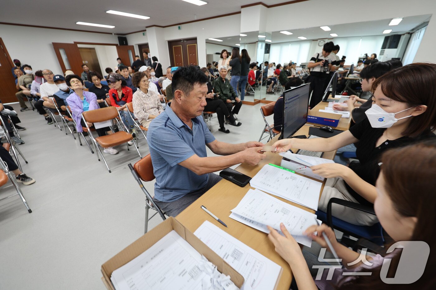 본문 이미지 - 2차 민생회복 소비쿠폰 신청 첫 날인 22일 광주 북구 두암3동 행정복지센터에 시민들이 신청 후 선불카드를 수령하고 있다. 2025.9.22/뉴스1 ⓒ News1 박지현 기자