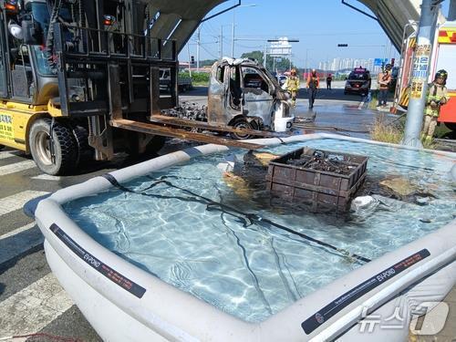 본문 이미지 - 지난 10일 오전 9시32분쯤 충북 음성군 금왕읍 유촌리 한 도로를 운행 중이던 1톤 화물차 적재함 배터리팩에서 불이 나 소방당국이 이동용 수조를 이용해 화재를 진압하고 있다./뉴스1