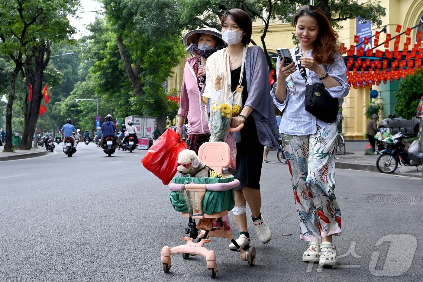 (하노이 AFP=뉴스1) 권영미 기자 = 22일 베트남 하노이의 거리에서 사람들이 개모차에 반려견을 태우고 함께 걷고 있다.2025.09.22.ⓒ AFP=뉴스1