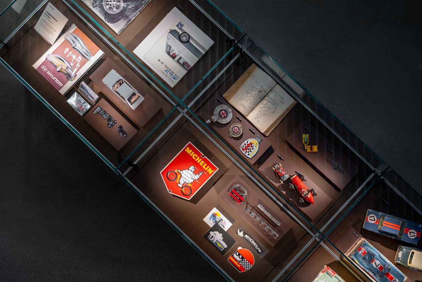 본문 이미지 - 22일 서울 강남구 소재 현대자동차 브랜드 체험 공간인 '현대 모터스튜디오 서울' 1층 오토 라이브러리 진열장에 포르쉐 레이싱카 '917' 모형과 1950년대 영국 지도책, 이탈리아 내구 레이스 대회 '밀레 밀리아' 앰블럼, 현대차 '포니' 모형 등이 전시된 모습(현대차 제공). 2025.09.22.