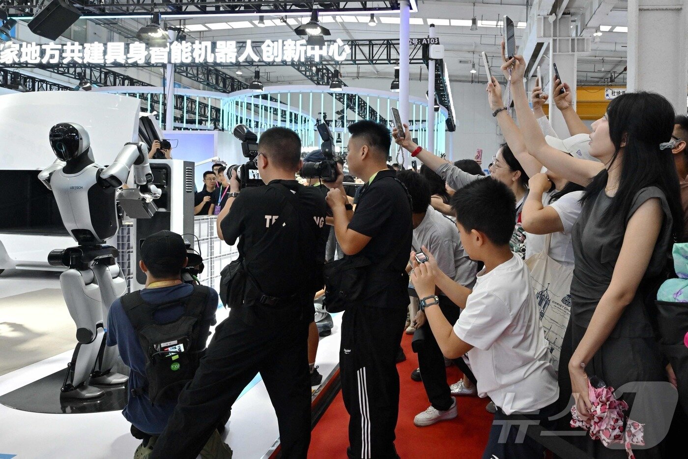 본문 이미지 - 중국 베이징에서 개최된 로봇박람회 관람객들이 유비테크의 워커S2가 스스로 배터리를 교환하는 장면을 지켜보고 있다. 2025.8.8 ⓒ AFP=뉴스1 ⓒ News1 정은지 특파원