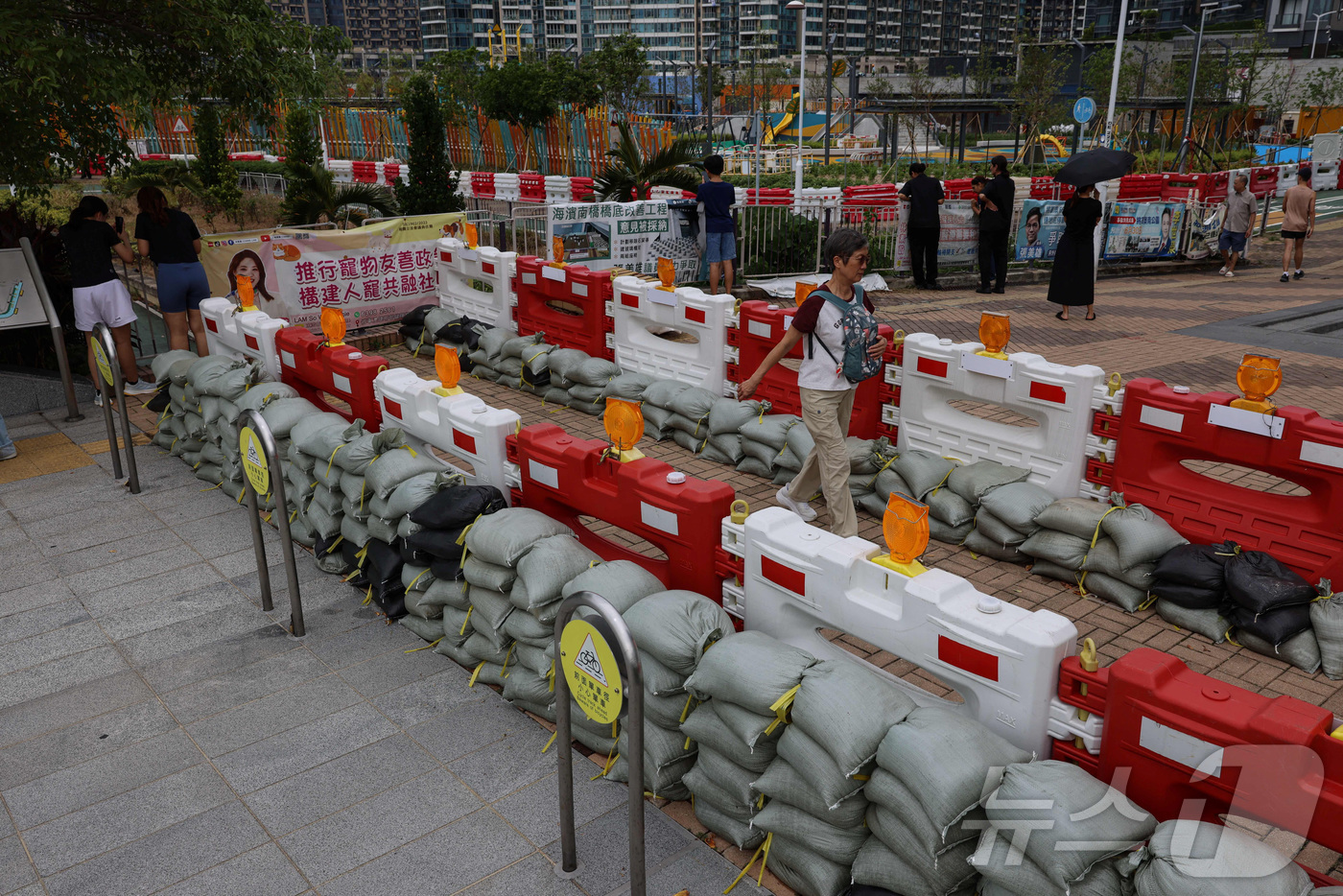 (홍콩 로이터=뉴스1) 권준언 기자 = 23일(현지시간) 홍콩에서 태풍 라가사로 인한 홍수를 막기 위해 놓인 모래주머니 벽을 따라 이동하는 시민들의 모습. 2025.09.23.ⓒ …