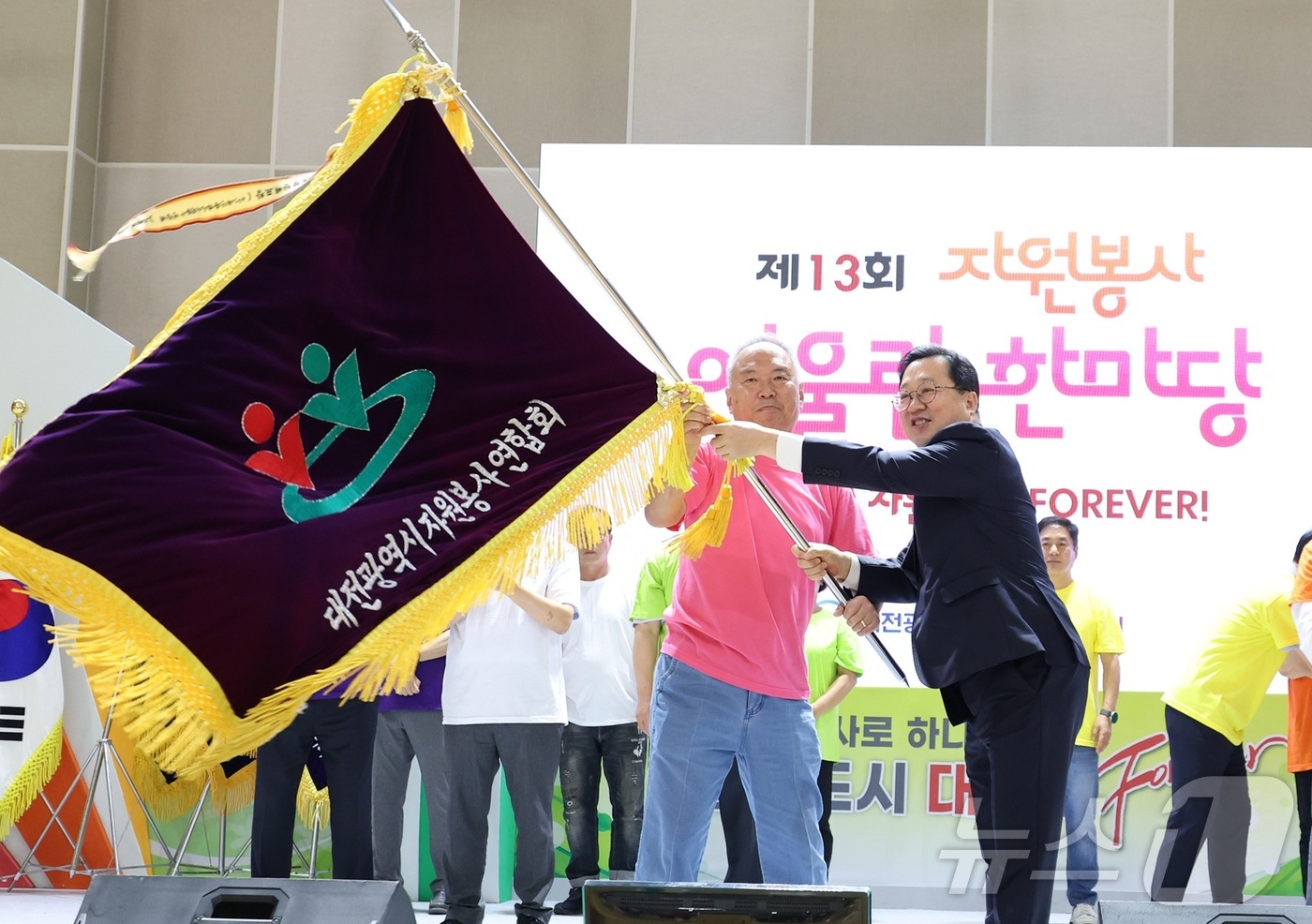 (대전=뉴스1) 김기태 기자 = 이장우 대전시장이 23일 한밭체육관에서 '제13회 자원봉사 어울림 한마당'에 참석해 연합회기를 전달받고 있다.이날 행사에는 대전시 자원봉사연합회와 …