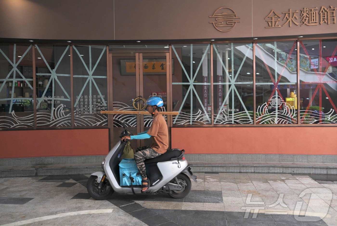 (주하이 AFP=뉴스1) 권영미 기자 = 23일 중국 남부 광둥성 주하이에서 한 배달원이 초강력 태풍 라가사가 상륙에 대비해 창문에 테이프가 붙은 식당 앞을 지나가고 있다. 202 …