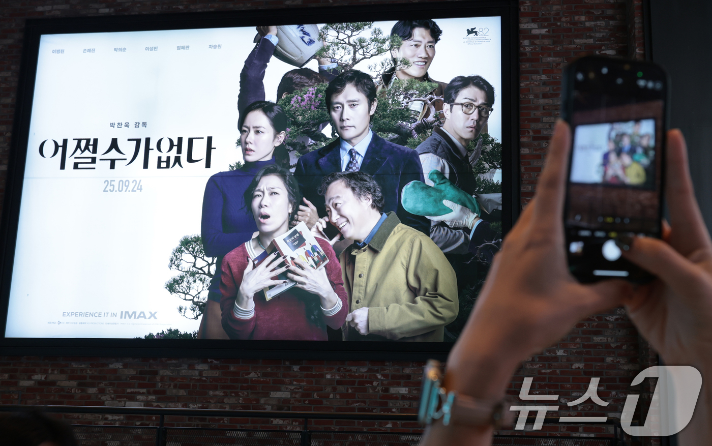 (서울=뉴스1) 권현진 기자 = 25일 서울도심의 한 영화관에서 관객이 박찬욱 감독의 영화 '어쩔수가없다' 포스터 사진을 찍고 있다.이날 영화진흥위원회 영화관 입장권 통합전산망 집 …