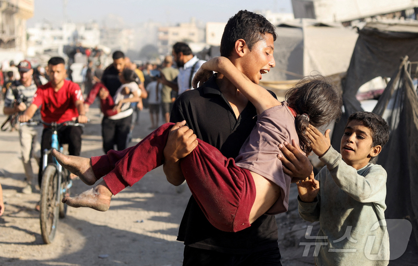 (가자시티 로이터=뉴스1) 윤다정 기자 = 7일(현지시간) 가자시티의 알자지라 텐트에 대한 이스라엘 공습 직후 한 팔레스타인 소년이 부상당한 소녀를 안아 들고 있다. 2025.09 …