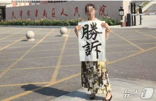 본문 이미지 - 법원 앞의 추이씨. 승소라는 글귀를 들고 있다.  - SCMP 갈무리