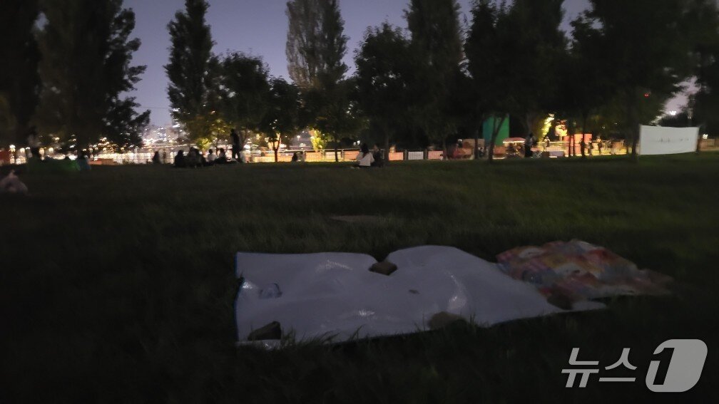본문 이미지 - '2025 서울세계불꽃축제' 개최 전날인 26일 서울 영등포구 여의도한강공원 일대에서 빈 돗자리가 무거운 돌로 고정돼 있다.