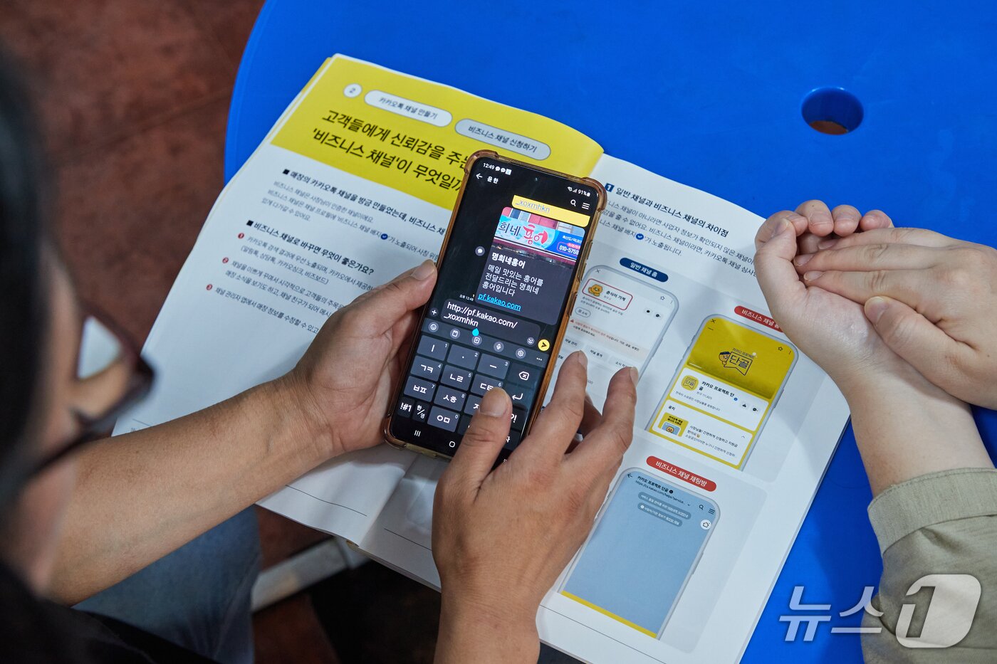 본문 이미지 - 카카오의 지역 청년 튜터가 목포 시장 상인에게 톡채널 개설 방법을 교육하는 모습 &#40;카카오 제공&#41;