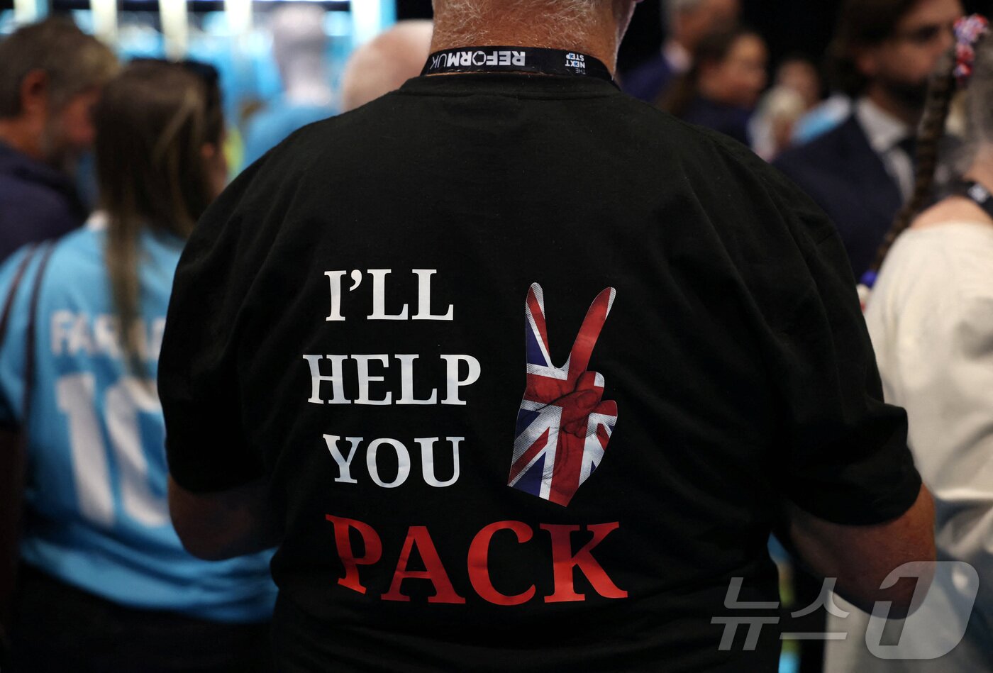 본문 이미지 - 영국 개혁당 전당대회 참석자가 &#39;짐 싸는 거 도와 줄게&#39;라고 적힌 티셔츠를 입고 있다. 2025.09.06 ⓒ 로이터=뉴스1 ⓒ News1 이지예 객원기자