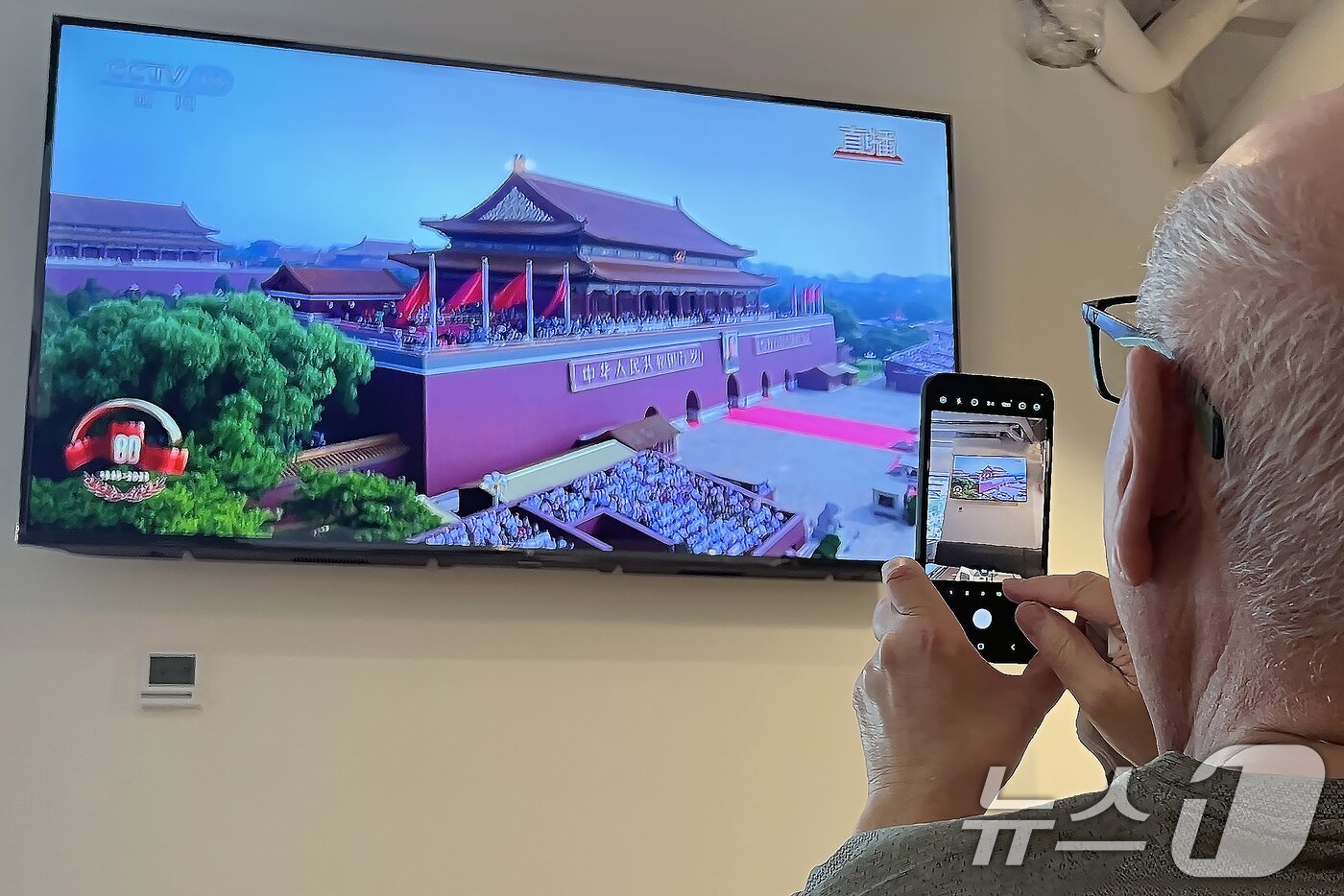 본문 이미지 - 중국 &#39;전승절&#39;&#40;항일전쟁 및 반파시스트 전쟁 승리&#41; 80주년인 3일 중국 베이징의 한 호텔 식당에서 외국인이 전승절 기념 열병식을 TV 중계 화면을 촬영하고 있다. 2025.9.3/뉴스1 ⓒ News1 박정호 기자