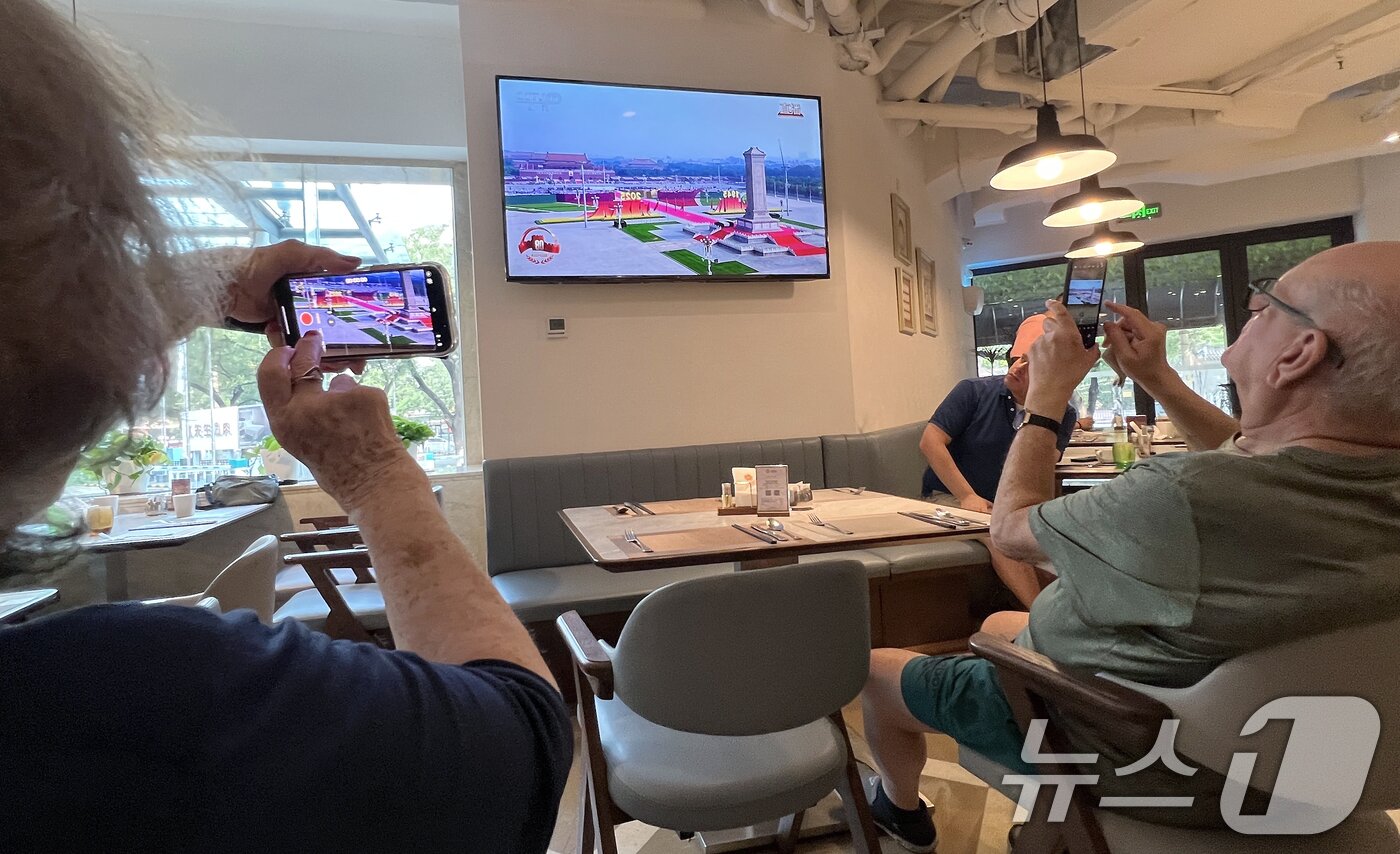 본문 이미지 - 중국 &#39;전승절&#39;&#40;항일전쟁 및 반파시스트 전쟁 승리&#41; 80주년인 3일 중국 베이징의 한 호텔 식당에서 외국인들이 전승절 기념 열병식을 TV 중계 화면을 촬영하고 있다. 2025.9.3/뉴스1 ⓒ News1 박정호 기자