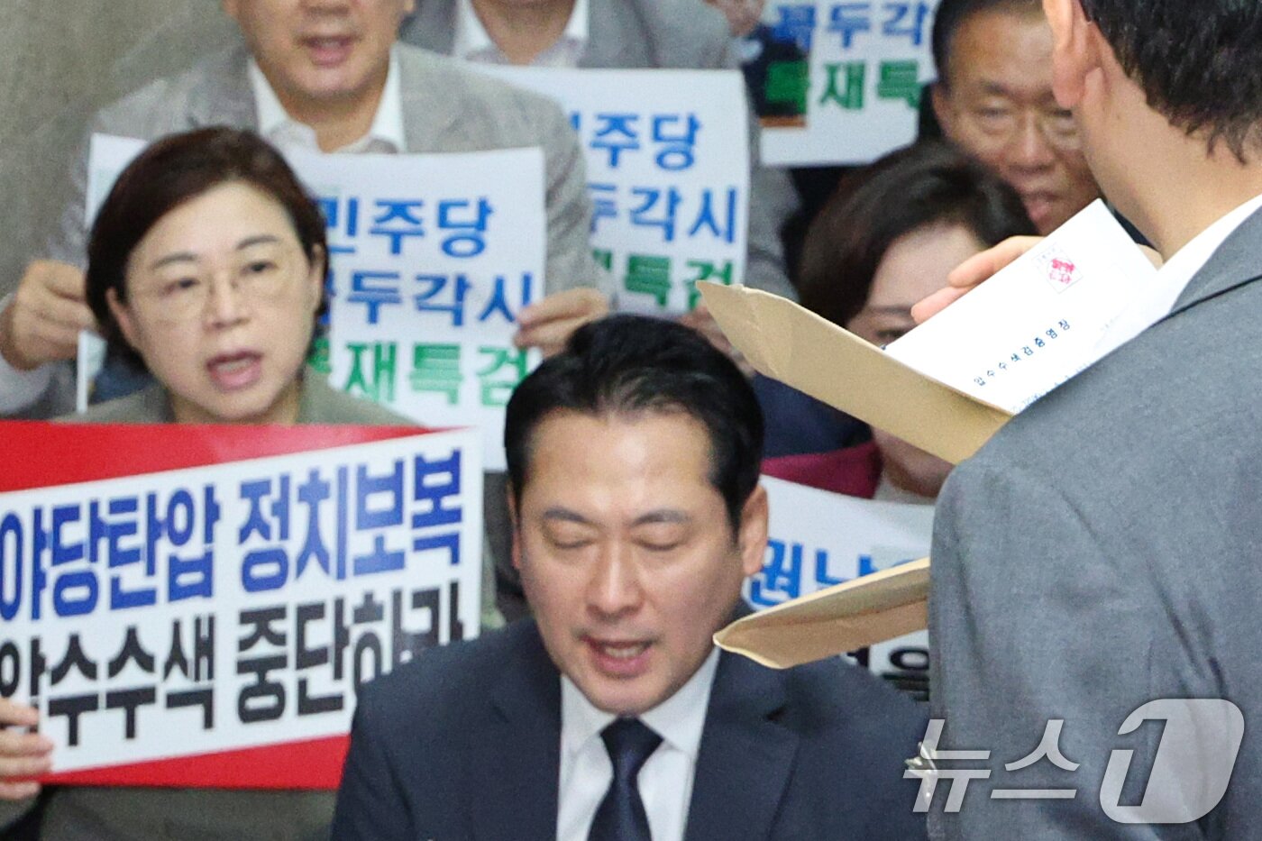 본문 이미지 - 국민의힘 의원들이 3일 오후 서울 여의도 국회 국민의힘 원내대표실 앞에서 긴급 의원총회를 가진 가운데 내란특검 수사관들이 원내대표실 압수수색에 나서며 영장을 꺼내고 있다. 2025.9.3/뉴스1 ⓒ News1 신웅수 기자