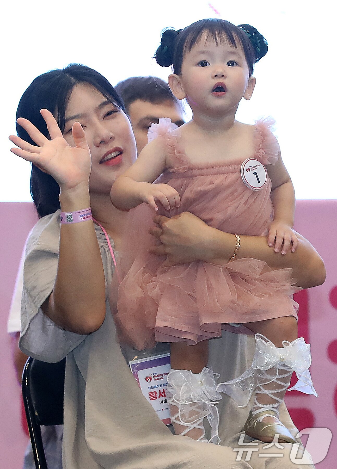 본문 이미지 - 5일 부산 해운대구 벡스코 제1전시장에서 열린 '제1회 헬시·큐티 베이비 페스티벌'에서 큐티 베이비 부문에 참가한 아기가 부모와 함께 무대에 올라 관객석을 바라보고 있다.  2025.9.5/뉴스1 ⓒ News1 윤일지 기자
