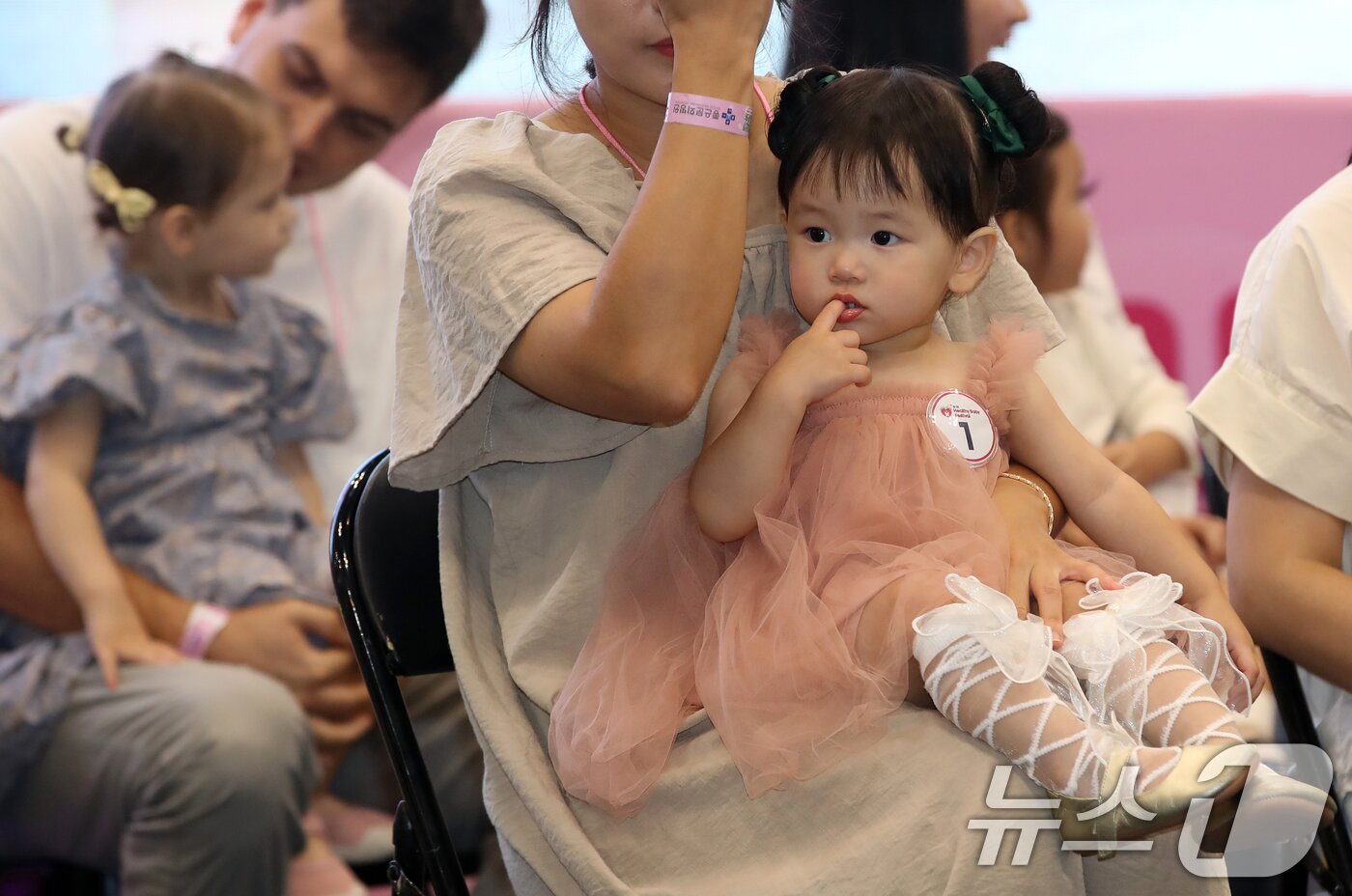 본문 이미지 - 5일 부산 해운대구 벡스코 제1전시장에서 열린 '제1회 헬시·큐티 베이비 페스티벌'에서 큐티 베이비 부문에 참가한 아기들이 부모와 함께 무대에 올라 관객석을 바라보고 있다.  2025.9.5/뉴스1 ⓒ News1 윤일지 기자