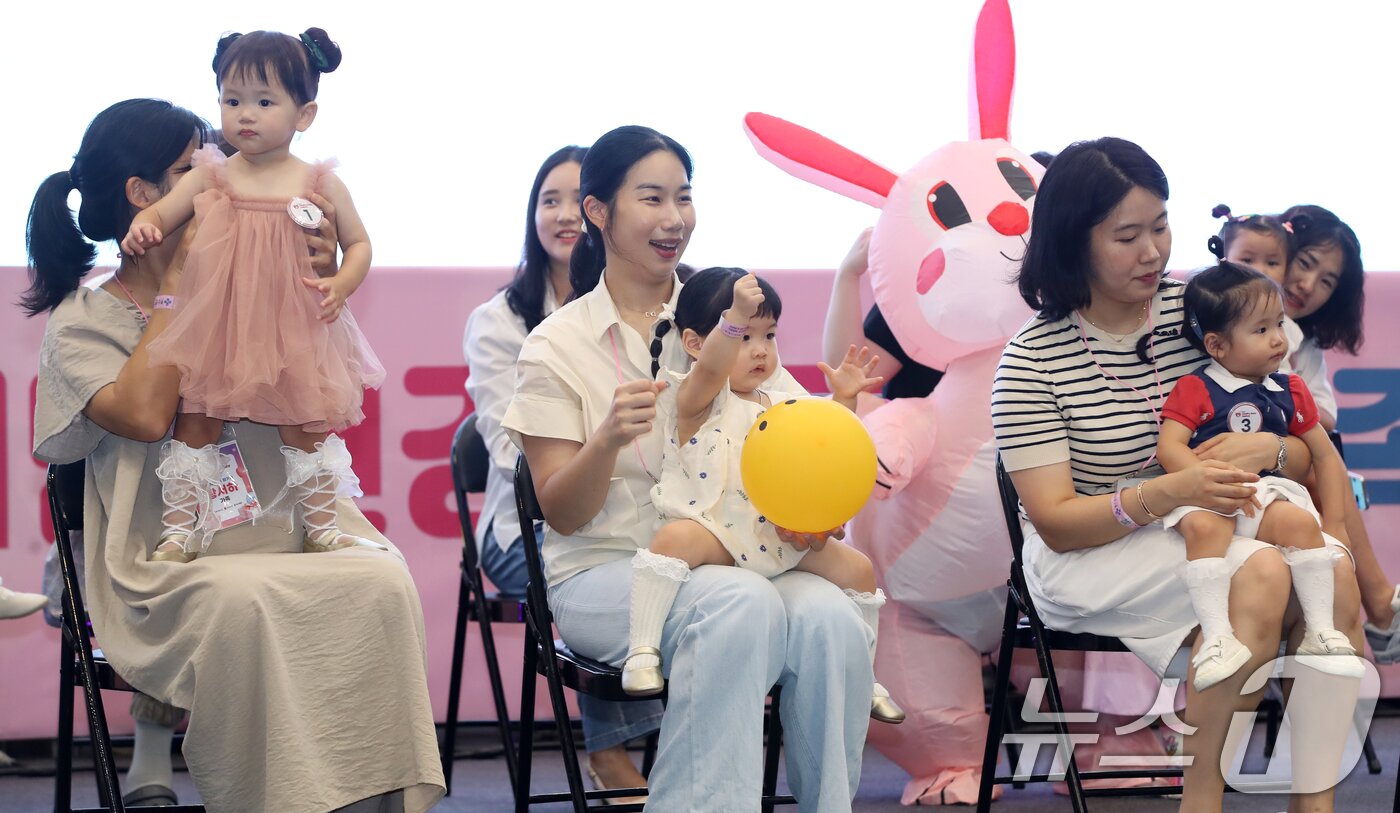 본문 이미지 - 5일 부산 해운대구 벡스코 제1전시장에서 열린 '제1회 헬시·큐티 베이비 페스티벌'에서 큐티 베이비 부문에 참가한 아기들이 부모와 함께 무대에 올라 관객석을 바라보고 있다.  2025.9.5/뉴스1 ⓒ News1 윤일지 기자