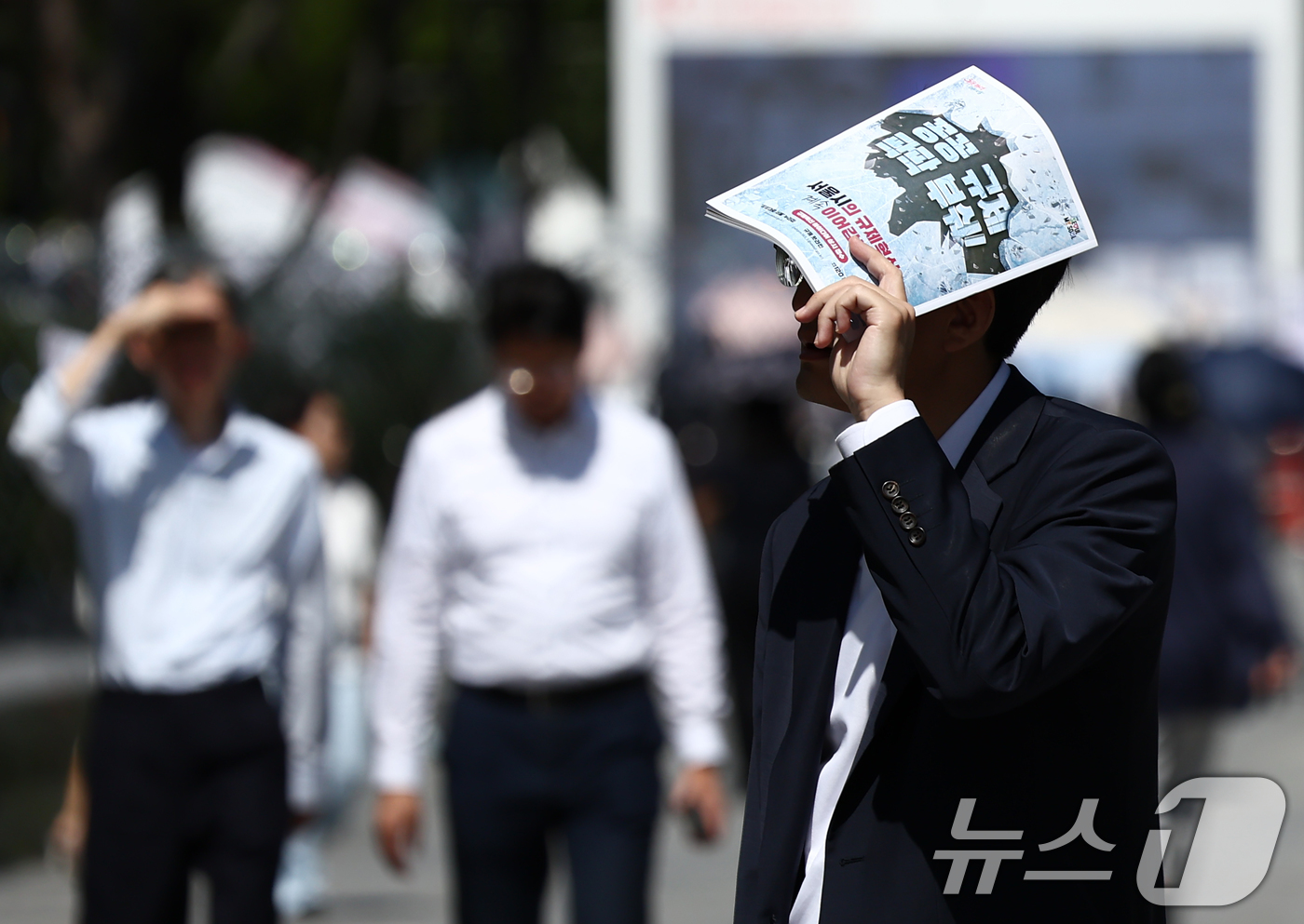 (서울=뉴스1) 김민지 기자 = 서울 낮 기온이 30도 이상 오르며 푹푹 찌는 무더위가 이어진 5일 오후 서울 종로구 광화문광장에서 시민이 책으로 햇볕을 가리며 발걸음을 옮기고 있 …