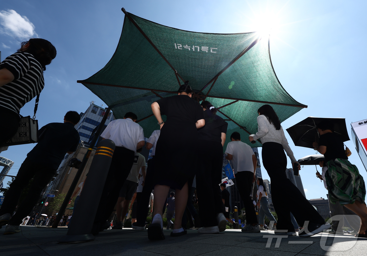 (서울=뉴스1) 김민지 기자 = 서울 낮 기온이 30도 이상 오르며 푹푹 찌는 무더위가 이어진 5일 오후 서울 종로구 세종대로에 시민들이 그늘막에서 햇볕을 피하고 있다. 2025. …