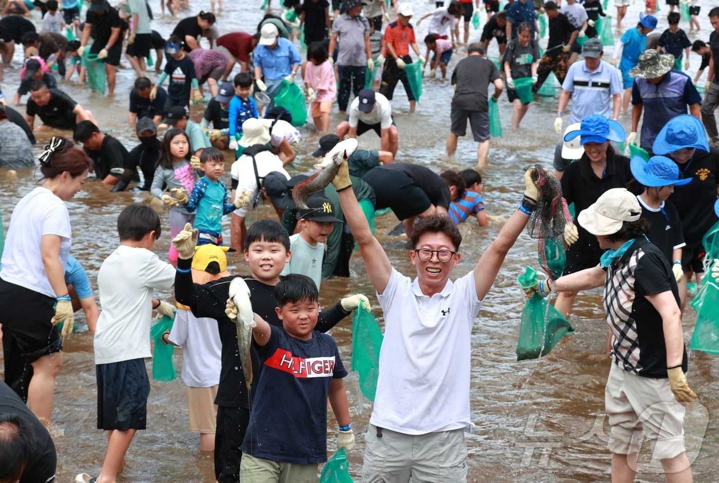 (괴산=뉴스1) 이성기 기자 = 6일 충북 괴산군 동진천에서 열린 2025 괴산고추축제 체험 프로그램 '고추물고기를 잡아라'에서 참가자들이 메기를 잡은 뒤 번쩍 들어보이고 있다. …