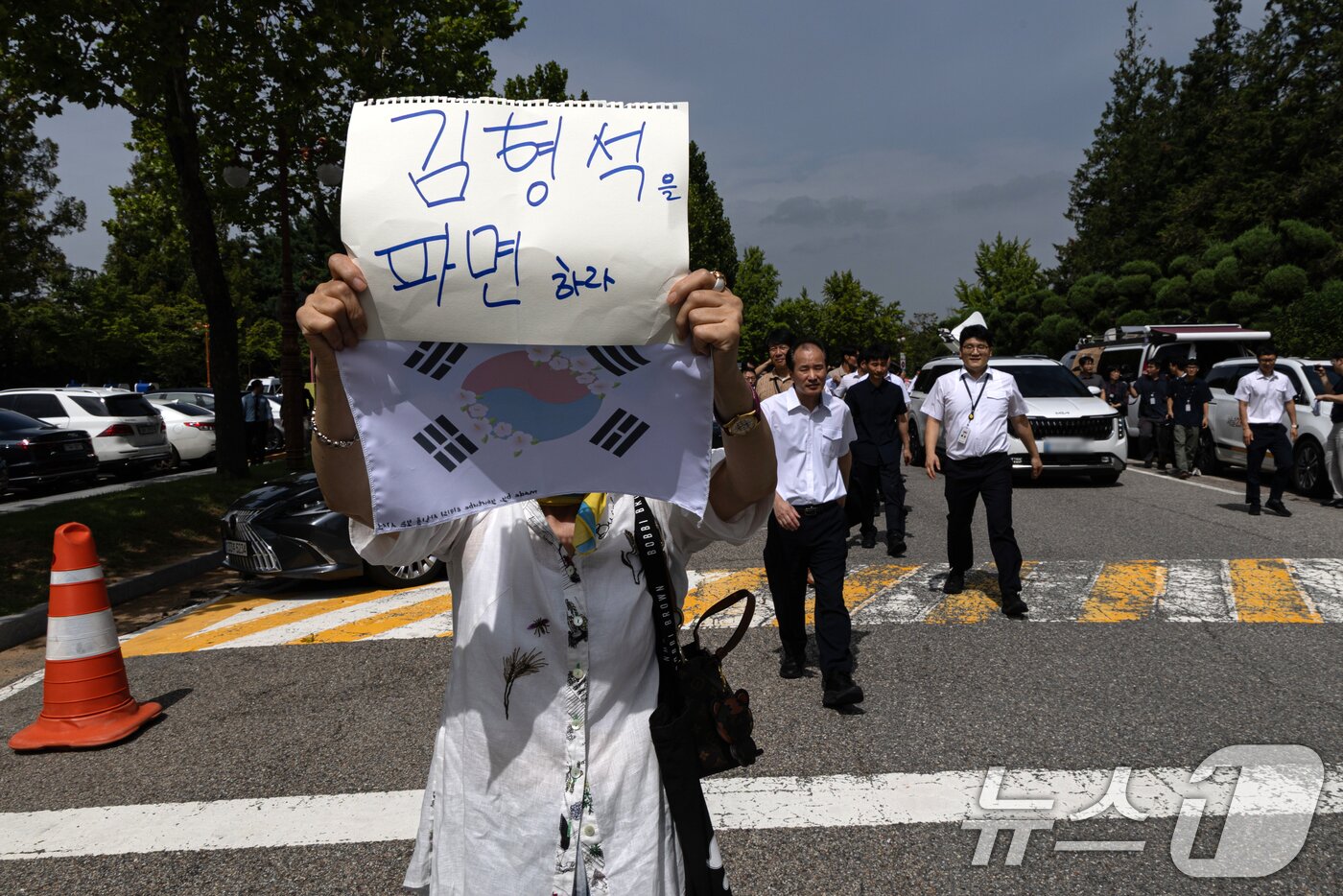 본문 이미지 - 8일 서울 여의도 국회 소통관 앞에서 한 시민이 김형석 독립기념관장의 퇴진을 요구하는 가운데 옆으로 김 관장이 탄 차량이 지나고 있다. ⓒ News1 이승배 기자