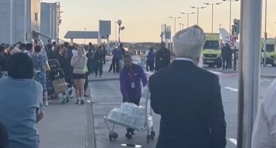 본문 이미지 - 공항 직원이 대피한 승객에게 물을 나눠주고 있다. <소셜미디어 엑스 사용자 @HarrySmithDev>