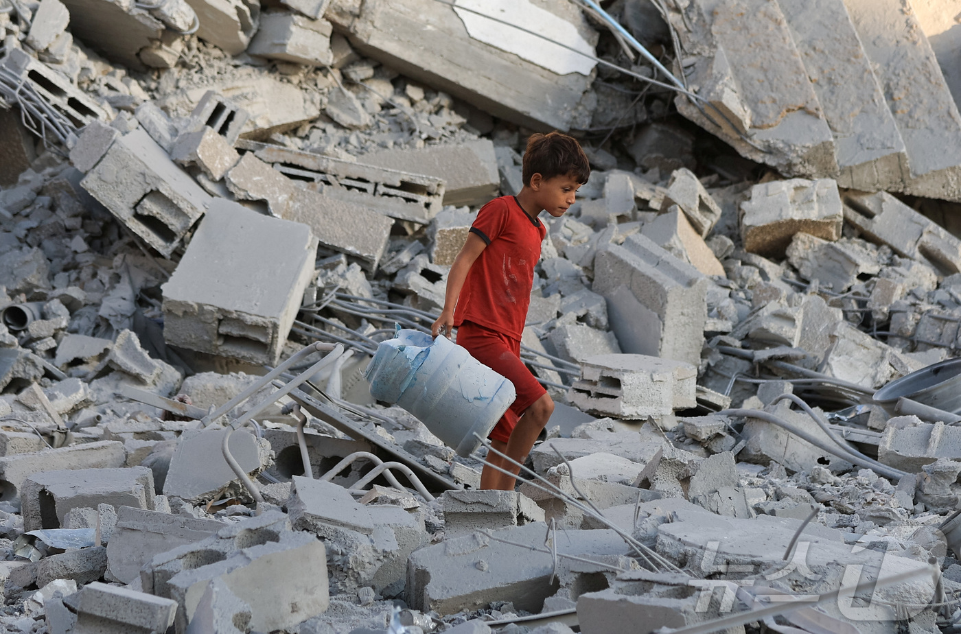 (가자 시티 로이터=뉴스1) 강서연 기자 = 9일(현지시간) 가자 시티에서 이스라엘의 야간 공습으로 무너진 주거 건물 현장에서 팔레스타인 소년이 깨진 물통을 들고 있다. 2025. …
