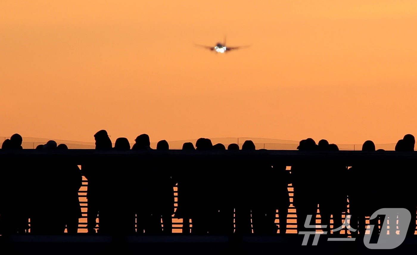 (대구=뉴스1) 공정식 기자 = 2026년 새해 첫날인 1일 오전 대구 동구 금호강 아양기찻길에서 새해 첫 일출을 기다리는 시민 위로 비행기가 날아가고 있다. 2026.1.1/뉴스 …