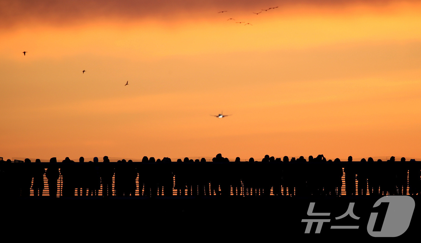 (대구=뉴스1) 공정식 기자 = 2026년 새해 첫날인 1일 오전 대구 동구 금호강 아양기찻길에서 새해 첫 일출을 기다리는 시민 위로 비행기가 날아가고 있다. 2026.1.1/뉴스 …