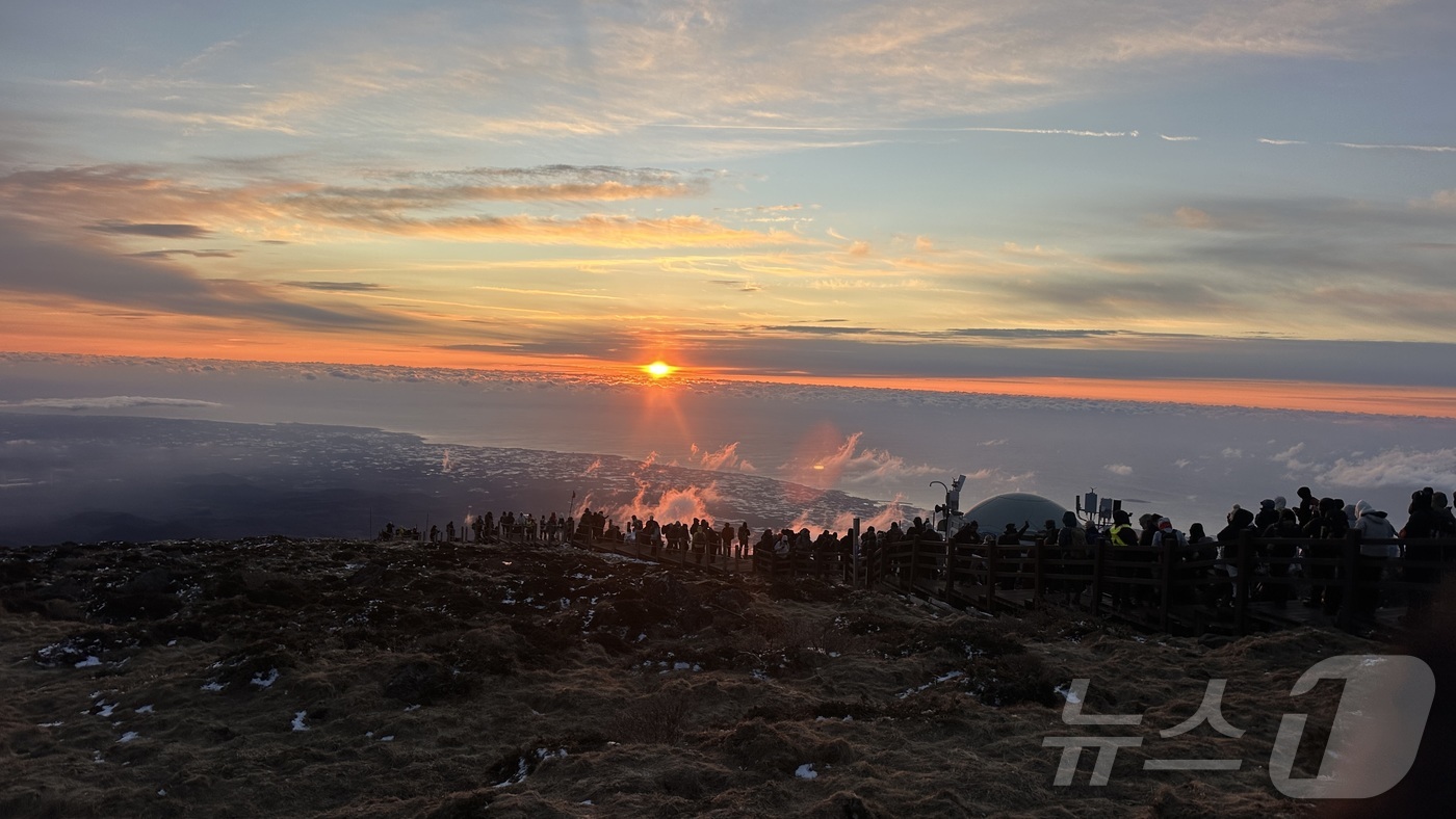 (제주=뉴스1) 강승남 기자 = 2026년 새해 첫날인 1일 제주 한라산 정상인 백록담에 오른 탐방객들이 구름 사이로 뜨는 해를 바라보고 있다.(한라산국립공원관리소 제공. 재판매 …