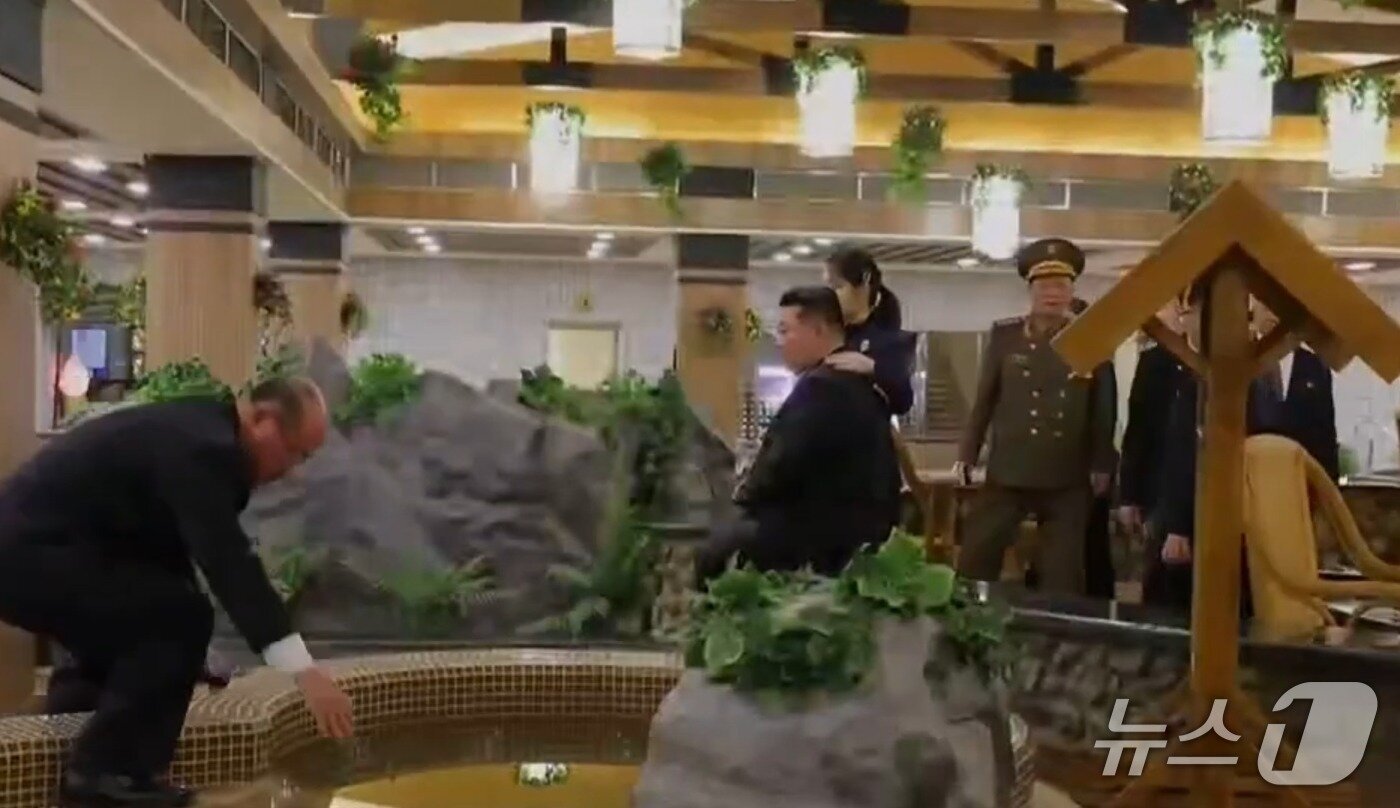 본문 이미지 - 지난해 12월 20일 진행된 삼지연시 관광지구 호텔 준공식 현장. 주애가 아버지인 김 총비서의 한쪽 어깨 위에 손을 올린 모습 (조선중앙TV 갈무리)