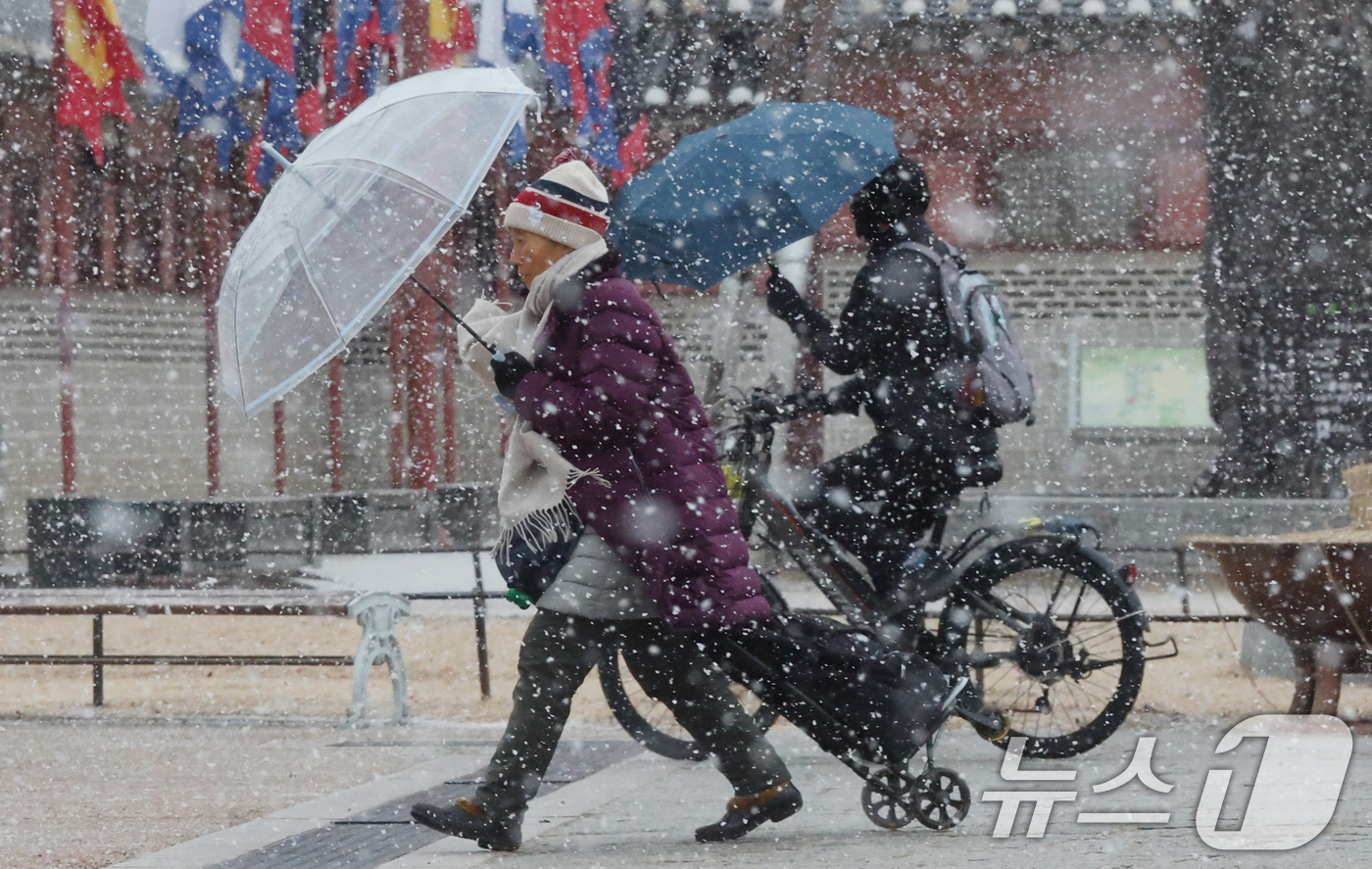 (수원=뉴스1) 김영운 기자 = 중부지방을 중심으로 눈이 내린 12일 경기 수원시 팔달구 화성행궁에서 시민들이 눈을 맞으며 걸어가고 있다. 2026.1.12/뉴스1